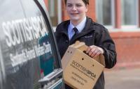 Member of staff behind an SSPCA van holding box 